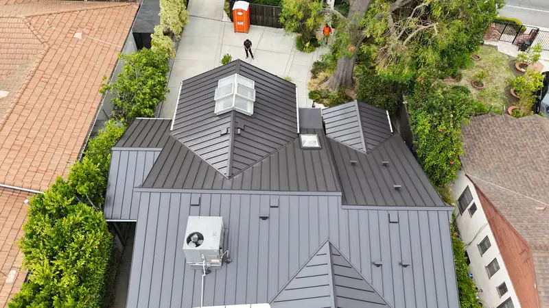 Aerial view of a dark standing seam metal roof with skylights, hips and gables