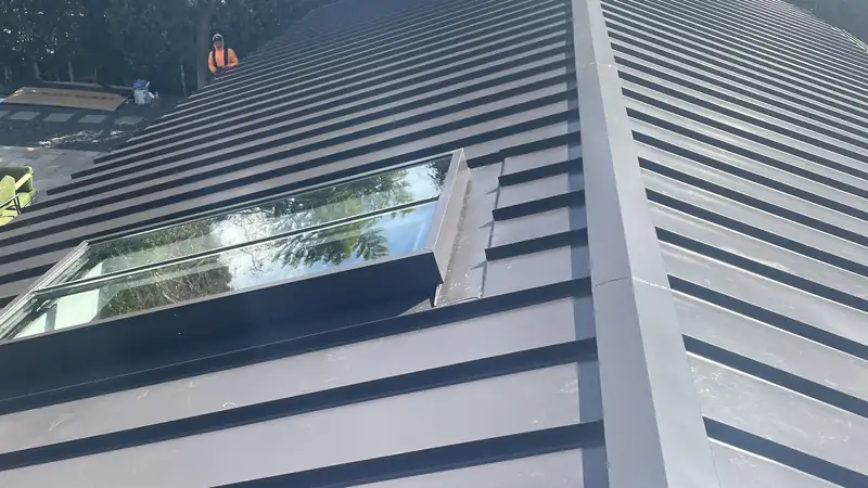 Standing seam metal roof panels and a skylight, with the raised seams running down the slope